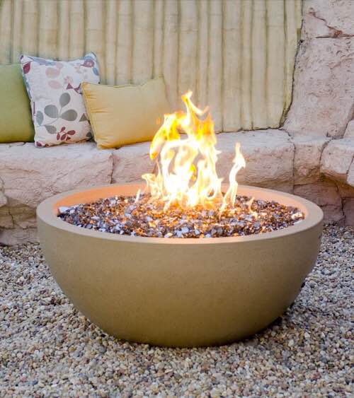 Custom Firepit burning with stone seating and pillows in the background. 